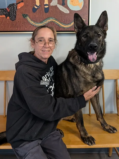 Kim G. sitting on a bench with her German Shepherd