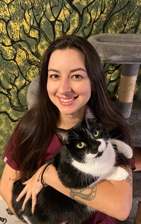 Sam smiling and holding a black and white cat
